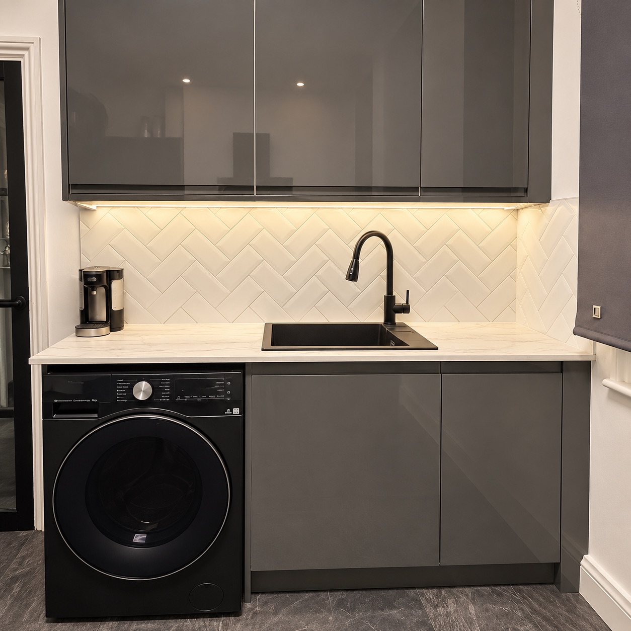 Completed sink area with black tap, pale worktop and herringbone tiling.
