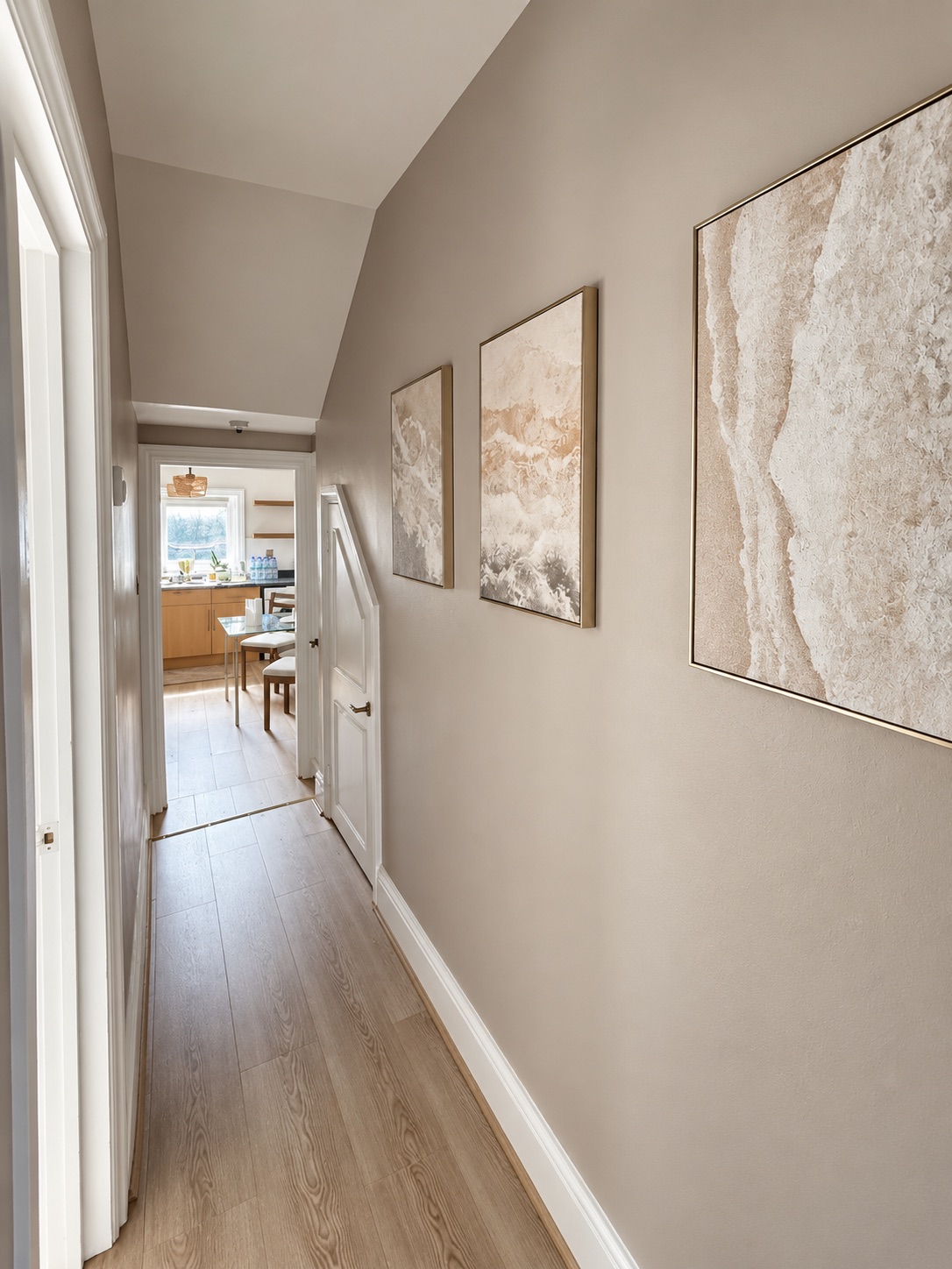 Laminate flooring through the corridor, with white skirting, doors and architraves.