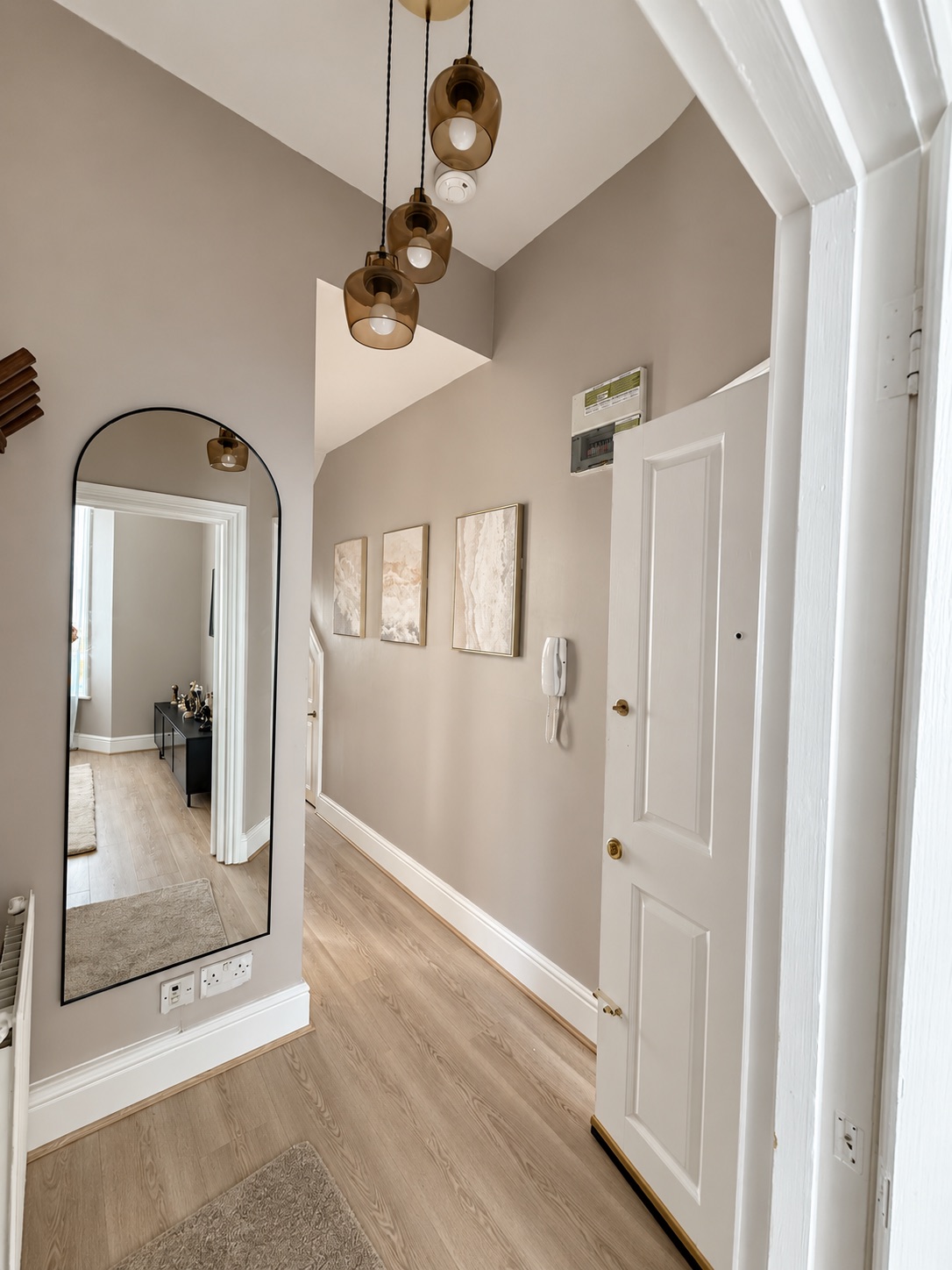 Entrance and hallway showing the laminate flooring, painted finishes, skirting and pendant fittings.