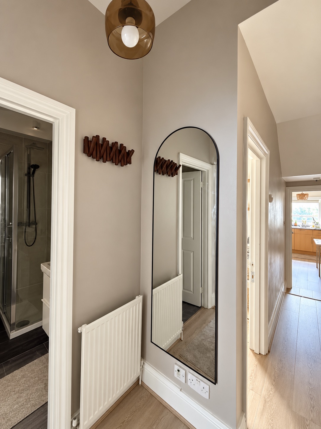 Hallway mirror and fittings, painted walls and white architraves at the adjoining doorways.