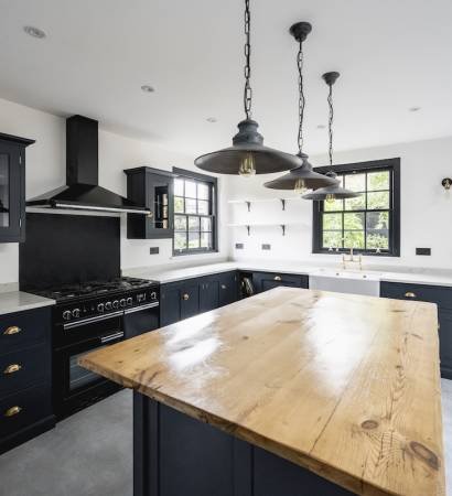 Expansive view of granite countertops, kitchen island, pendant lights, black accented cabinets and appliances, and access to outdoor patio.